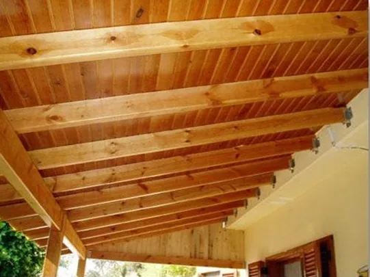 Perfiles de madera de sección rectangular sosteniendo un techo machihembrado